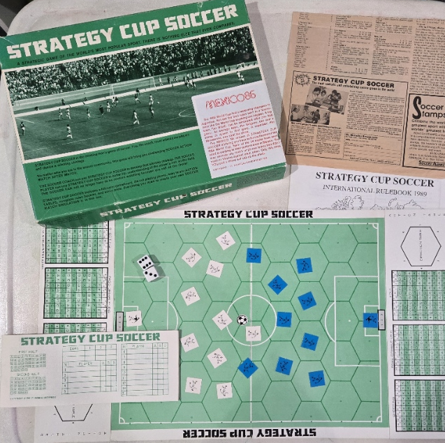 Complete Strategy Cup Soccer game set with board, box, rulebook, score pad, dice, player pieces, and Soccer America advertisement